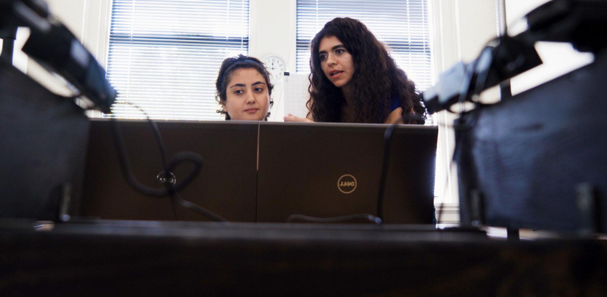 两个女生，一个在教另一个电脑.