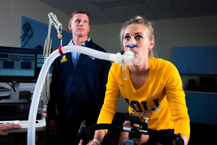 骑健身自行车的年轻女士用呼吸管测量氧气水平.