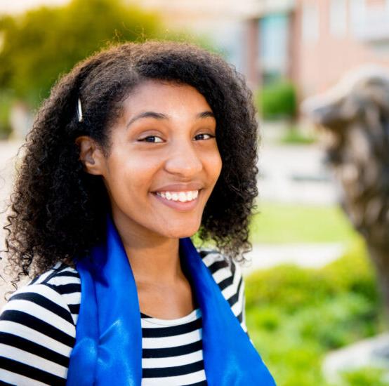 站在大学狮子雕像前微笑的年轻女子.